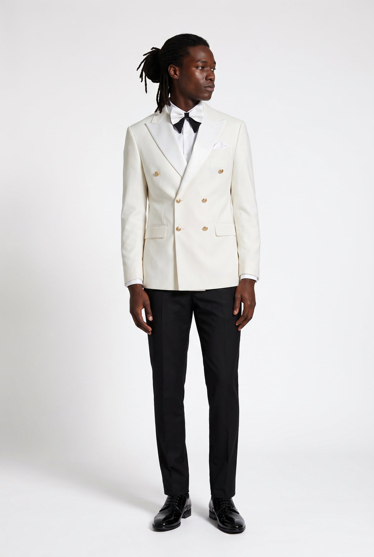 Man wearing a white double breasted tuxedo with a satin peak lapel and gold buttons