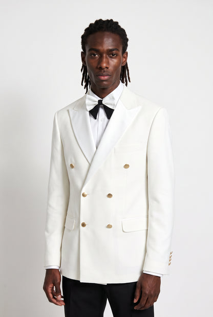 Half body view of the satin peak lapel and gold buttons on a white double breasted tuxedo