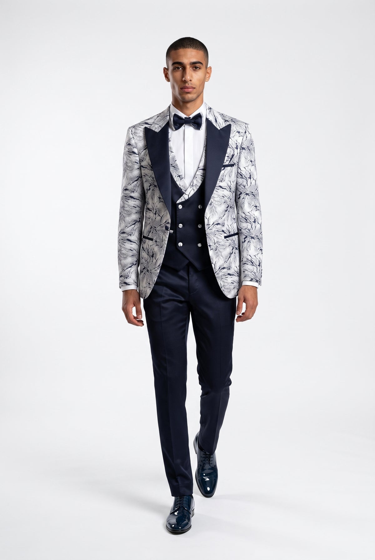 Man wearing a white lightning print tuxedo with a navy satin peak lapel, navy trouser full view