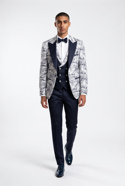 Man wearing a white lightning print tuxedo with a navy satin peak lapel, navy trouser full view