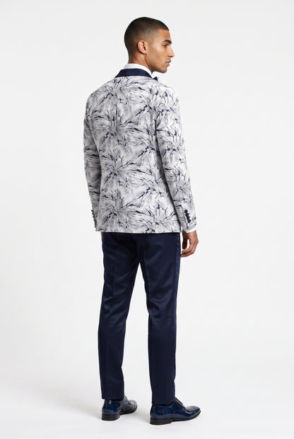 A man shown from the back wearing a white and navy print blazer, navy trousers, and navy dress shoes, photographed against a clean white studio background.