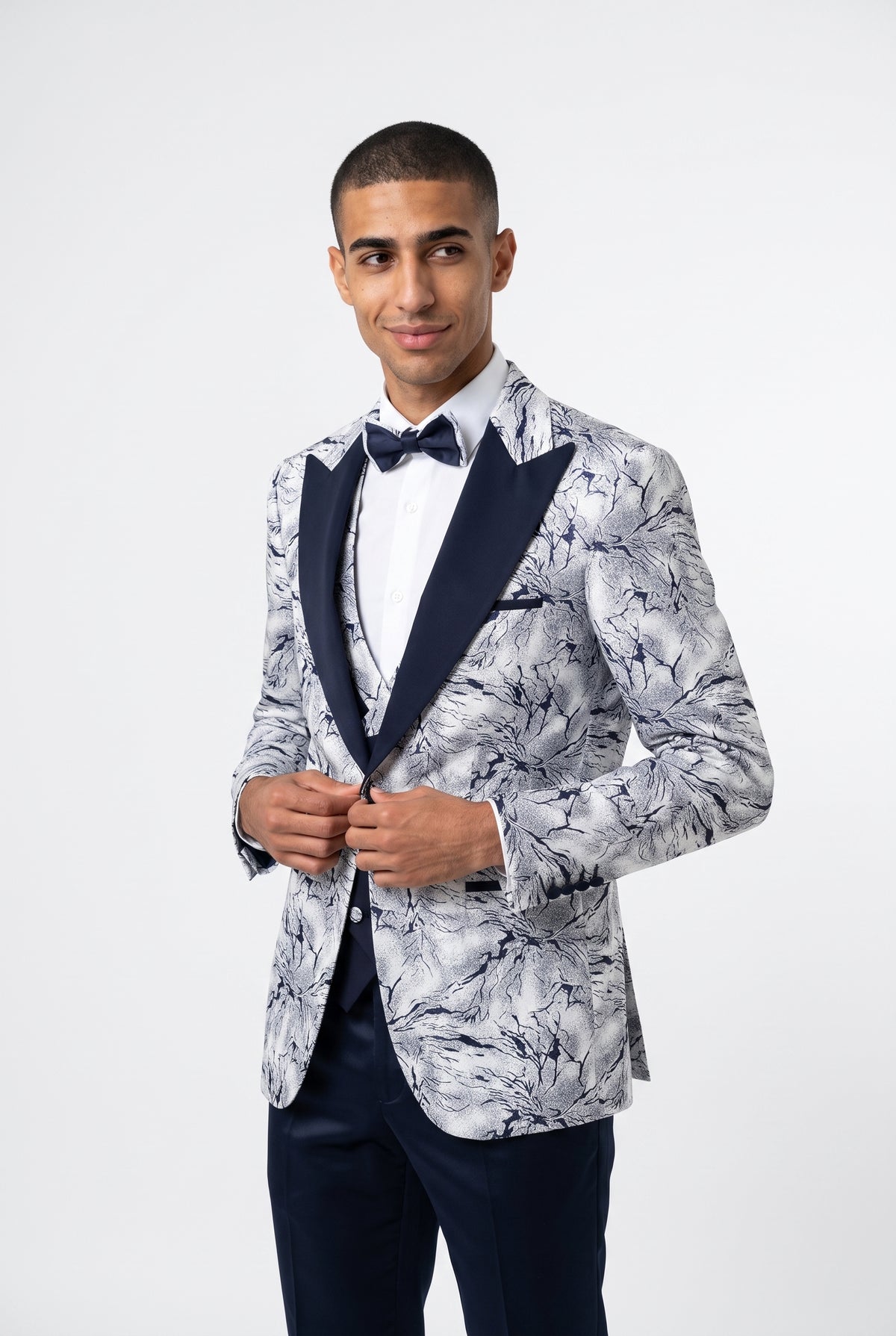Man wearing a white marble print tuxedo with a navy satin peak lapel 